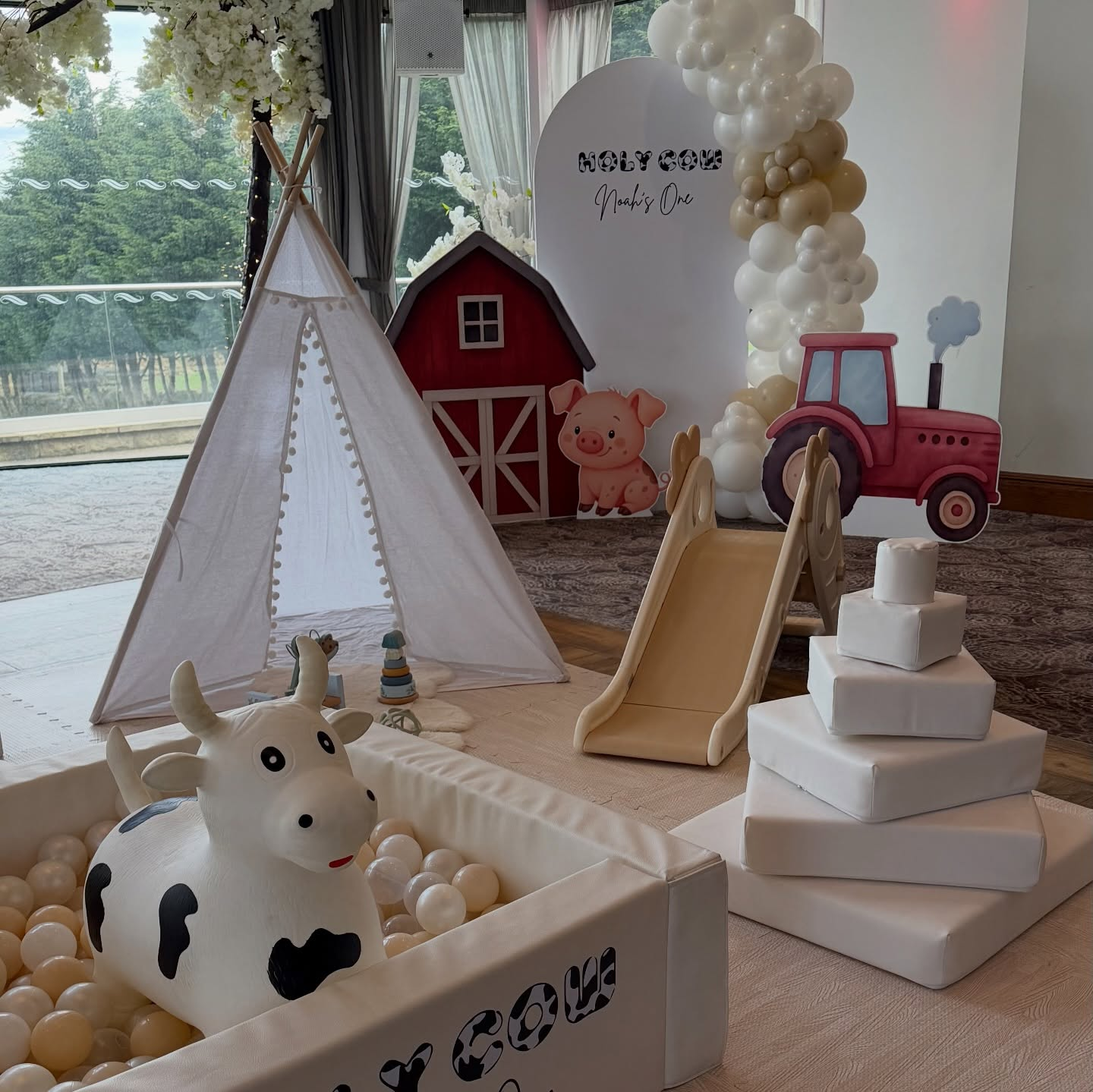 Holy Cow farm themed first birthday soft play with cow ball pit and barn backdrop
